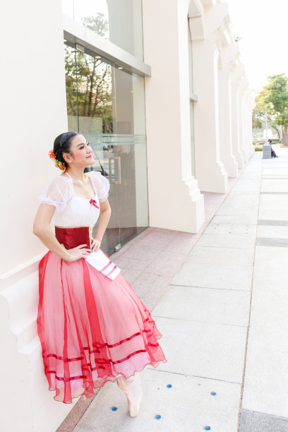 穿着白色和红色的浪漫的芭蕾舞服装的女芭蕾舞者用脚趾站着图片下载