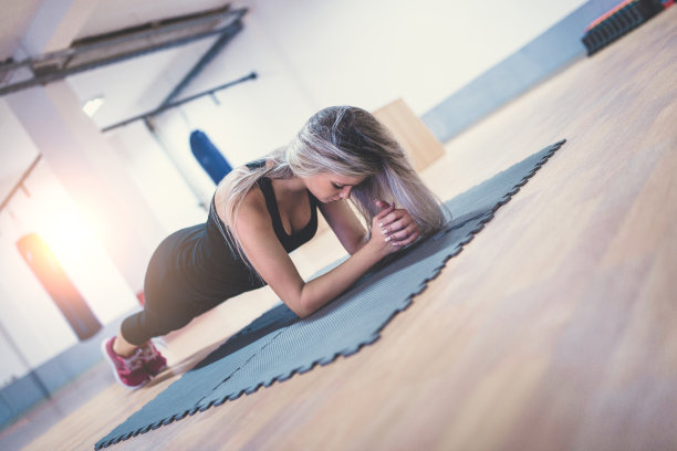 年轻女子在健身房做平板支撑锻炼腹肌图片下载