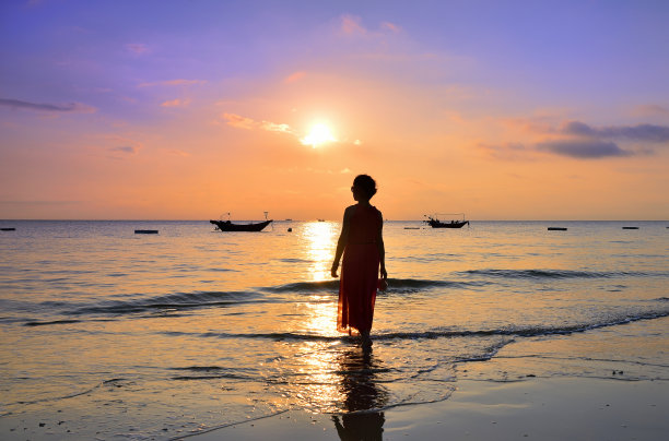 黄昏时分，一个女人站在海边，轮廓分明图片下载