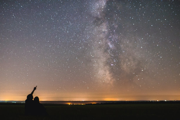 一对相爱的情侣在我们的家园银河系中心的星星下。两个人晚上在星空下素材图片