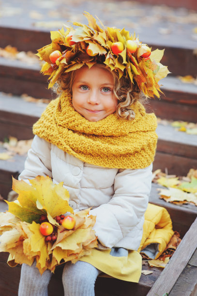 可爱可爱的蹒跚学步的小女孩与一束秋天的树叶和花环散步在公园或森林图片下载