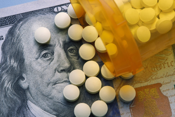 开着的处方药瓶子里的药丸洒在了一百美元上图片下载