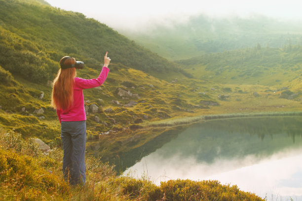 戴着虚拟现实眼镜的女人站在湖边图片下载