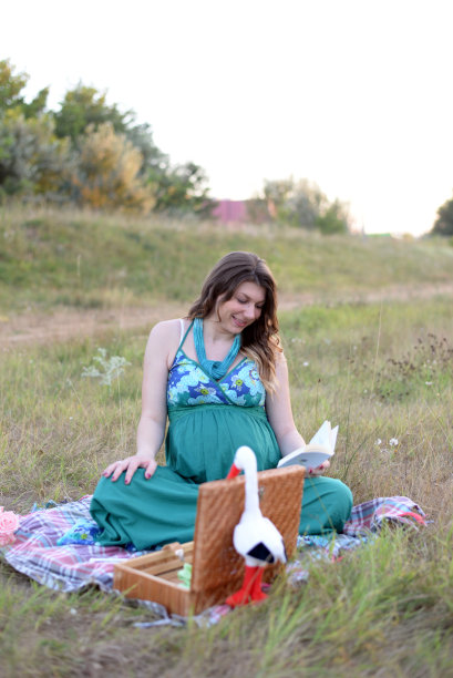 一个孕妇在草地上看书图片下载