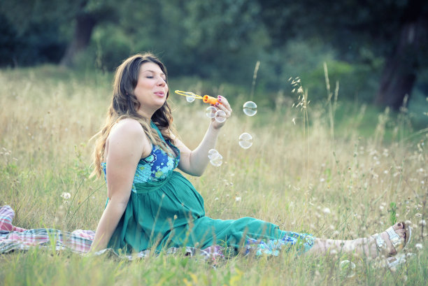 孕妇在草地上吹肥皂泡图片下载