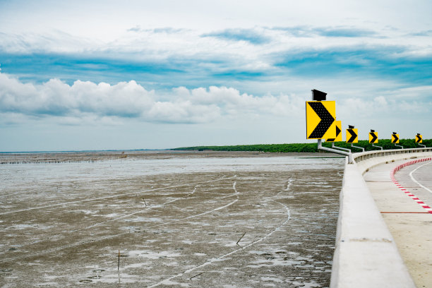 右转向灯上安装了太阳能电池，干净的混凝土路面上横越红树林，有美丽的天空为背景，风景如画图片下载