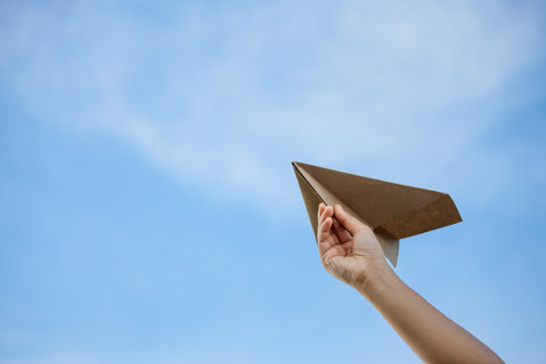手握纸飞机迎着天空素材图片