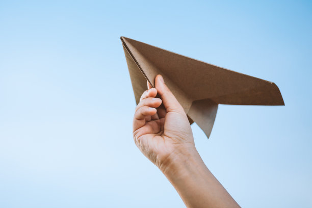 手握纸飞机迎着天空素材图片