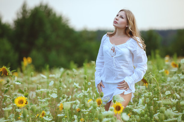 年轻女子在田野的花。图片下载