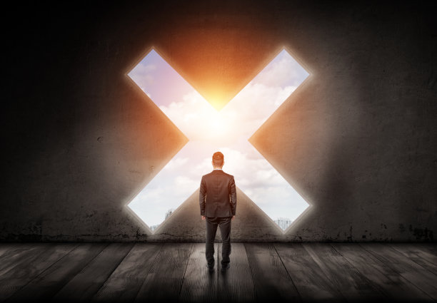 一个商人背对着水泥墙，看着一个十字形的洞图片下载