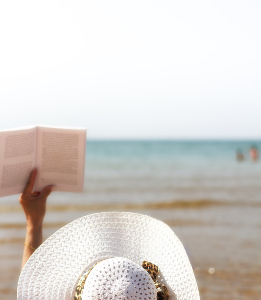 戴着白色太阳帽的女人在水边读书图片下载