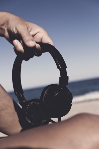 海滩上戴着耳机的年轻人图片下载