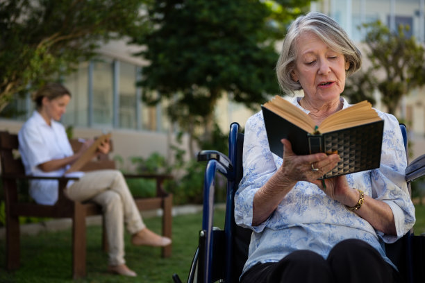 资深妇女阅读书籍，而医生坐在背景图片下载