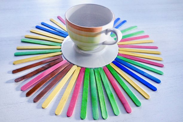 彩色的木制冰棒棍周围躺着一个空杯子图片下载