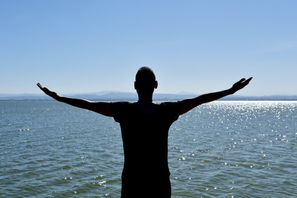 在大海前面挥舞着手臂的人图片下载