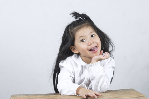 肖像欢快的一个有趣可爱的亚洲女孩在木制桌子上拷贝空间上的白色背景。图片下载
