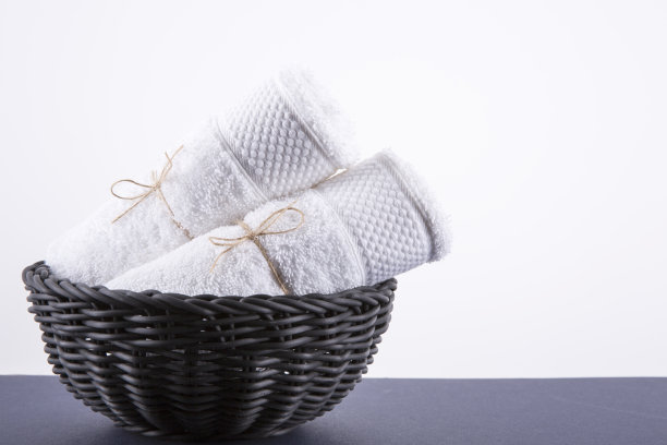 两条白毛巾放在黑篮子里。背景是白色的。图片下载