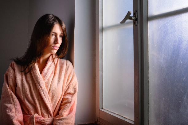 年轻女性癌症患者透过医院的窗户向外看图片下载