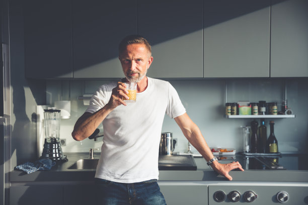 胡子成熟的男人在厨房拿着酒杯图片下载