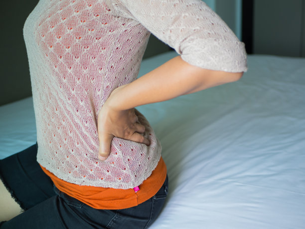 特写女人的手握着她的腰背部疼痛。医疗保健的概念。素材图片