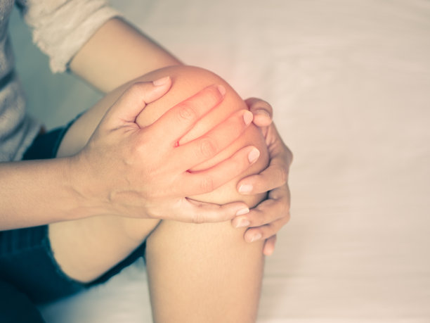 复古风格的年轻女性按摩她疼痛的膝盖，医疗保健的理念。图片下载