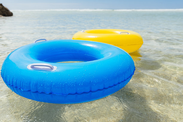 黄色和蓝色的橡胶圈漂浮在清澈的蓝色海洋上，康沃尔。图片下载