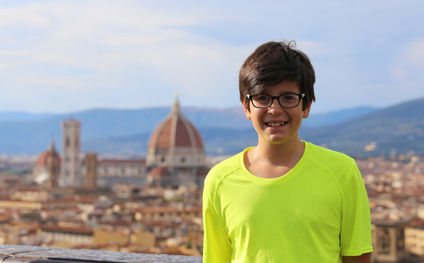 微笑的男孩与黑色的头发和背景的城市FL图片下载