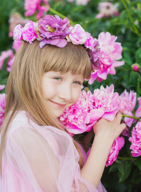 漂亮的小女孩脸上捧着一朵粉红色的牡丹图片下载