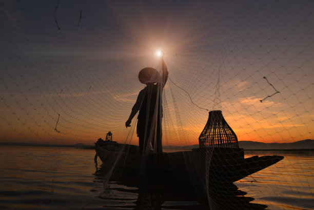 日出时分，传统渔民撒网捕鱼的剪影。图片下载