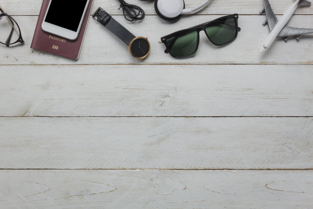 俯视图配件必不可少的旅行和技术背景概念。几件适合青少年或成人旅行者的物品。现代质朴的白色木制办公桌上的物品和花样繁多。图片下载