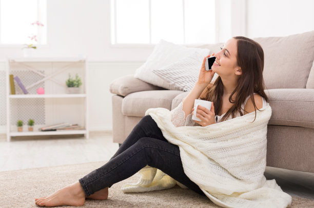 舒适的家。裹着毯子，拿着手机的女孩图片下载