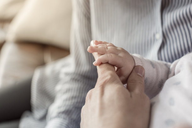 婴儿在母亲的膝上，握着她的手指图片下载