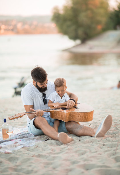 害羞的小男孩跟他爸爸学弹吉他图片下载