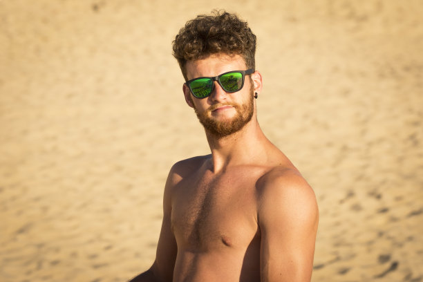 年轻的男性在海滩上看镜头图片下载
