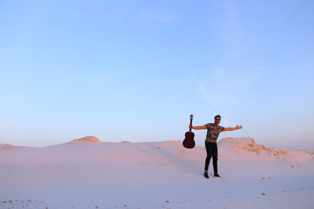 被沙漠美景所启发弹吉他的阿拉伯男子图片下载