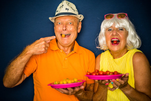 色彩汹涌的时尚老年人，愉快的老年夫妇吃西红柿图片下载