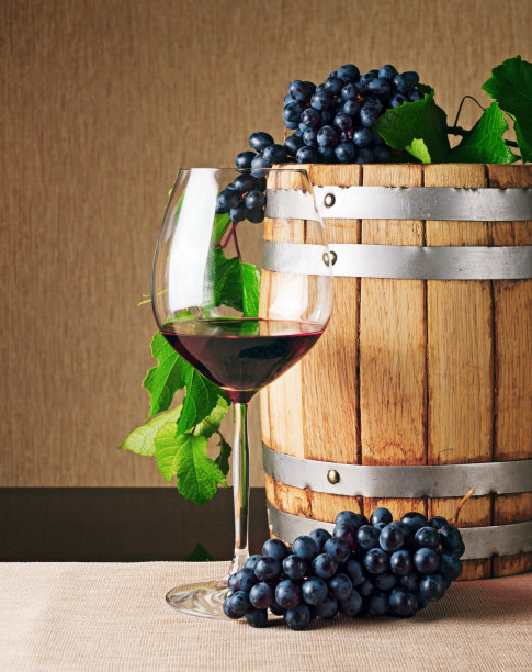 桌子上有一个木制的酒桶和一杯红酒图片下载