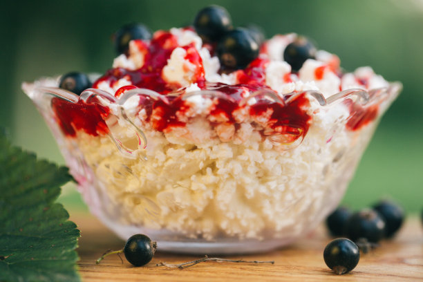 白软干酪，浆果果酱，新鲜黑加仑，一杯牛奶和一片新鲜烤面包在一个轻木制的背景。食物照片的概念。散景背景上的静物。美术风格图片下载