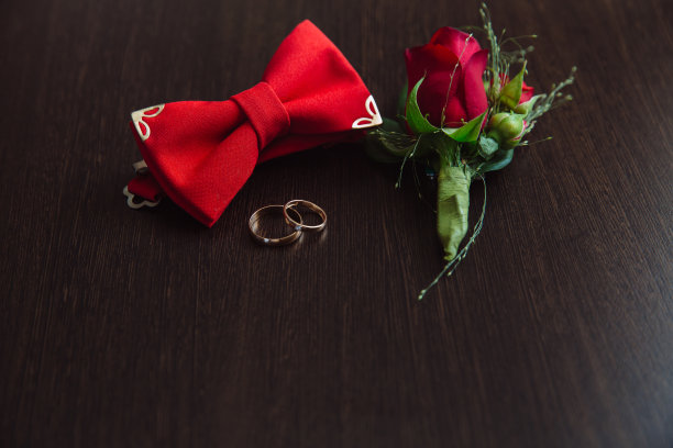 新郎婚礼配件。红色胸花，金戒指和棕色背景的蝴蝶结图片下载