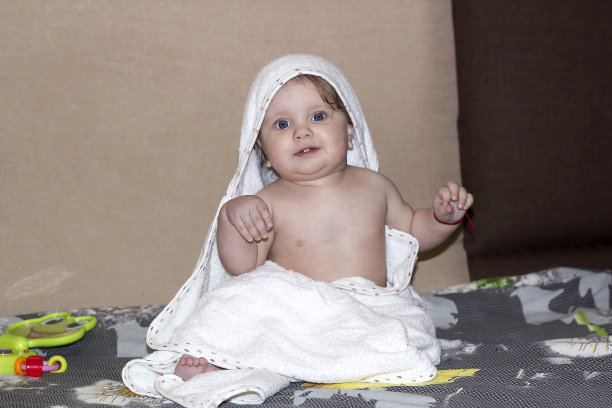 蓝眼睛的小孩沐浴后用毛巾坐着，开心地笑着图片下载