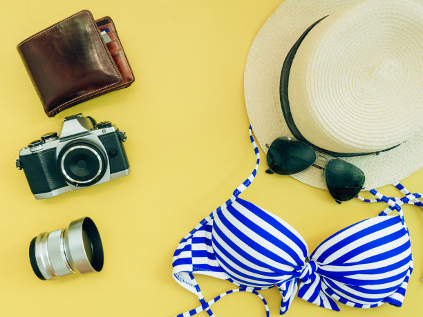 平铺组为夏季布料和配件(蓝色比基尼女孩，相机，钱包)与黄色背景图片下载