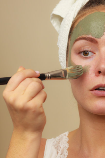 女人用刷泥面膜在她的脸上图片下载