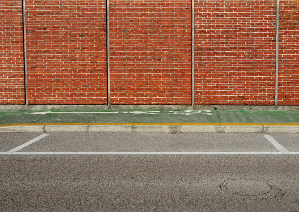 城市背景。在砖墙和街道之间的绿色自行车道。图片下载