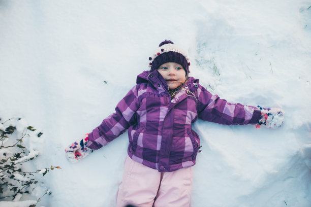 年轻的女孩做雪天使与大微笑在雪图片下载