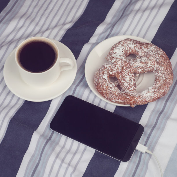 早上的早餐。舒适。一杯咖啡与新鲜的面包和电话，色调的照片图片下载