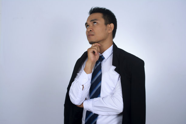 这是一幅年轻的亚洲商人肩上穿着黑色西装外套的思考姿势的照片图片下载