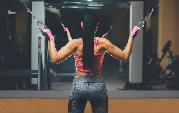 苗条，健美的女孩，站在健身房的镜子前锻炼。图片下载