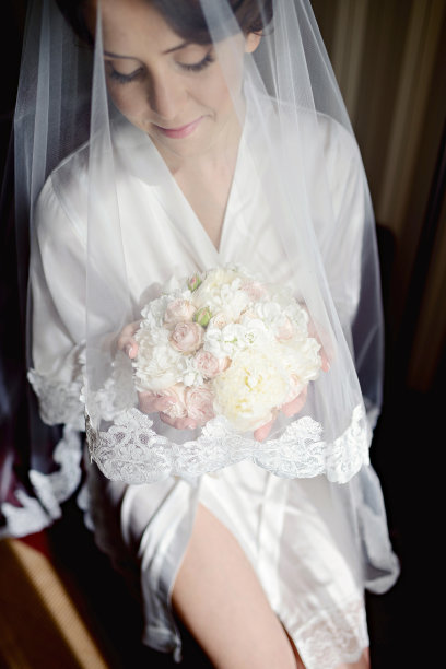 美丽的新娘穿着礼服与花束和蕾丝面纱室内图片下载