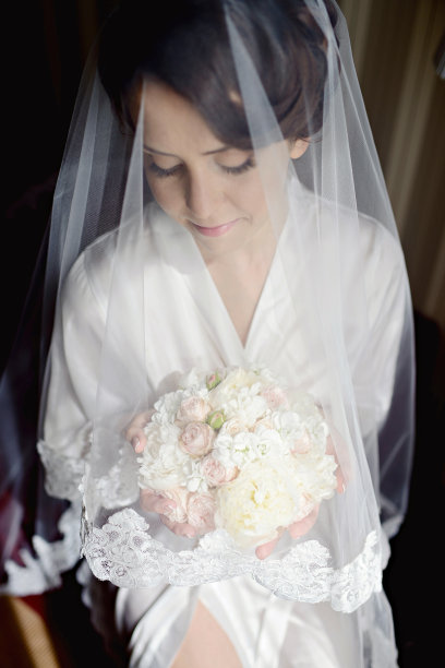 美丽的新娘穿着礼服与花束和蕾丝面纱室内图片下载