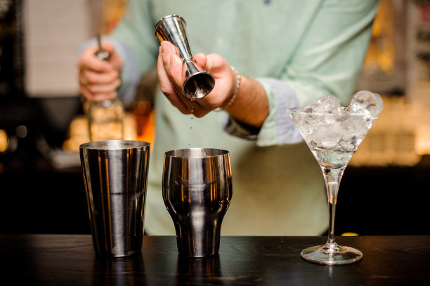调酒师用手把饮料倒进摇酒器准备鸡尾酒素材图片